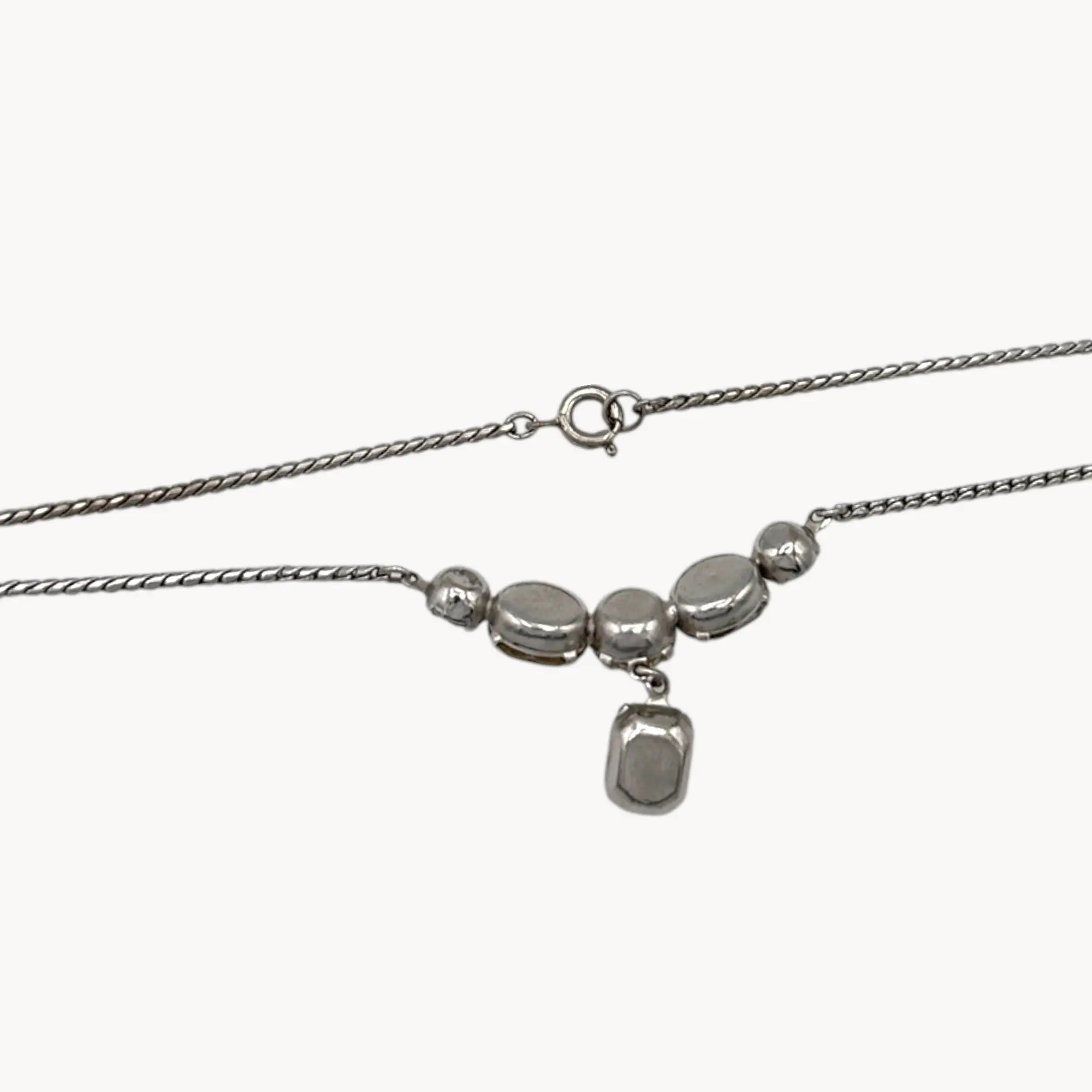 Back view of Vintage rhinestone pendant necklace with round and emerald-cut stones on white background.