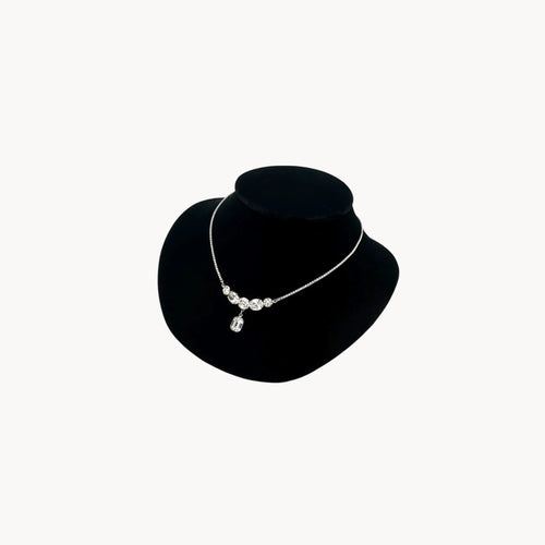 Side view of Vintage rhinestone pendant necklace with round and emerald-cut stones on black bust.