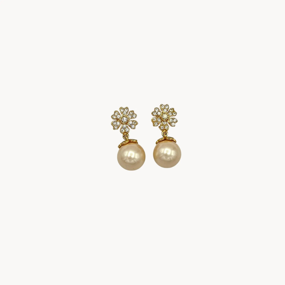 Close up Vintage unmarked clip-on earrings with crystal floral tops and faux pearl drops, 1990s bridal jewelry.