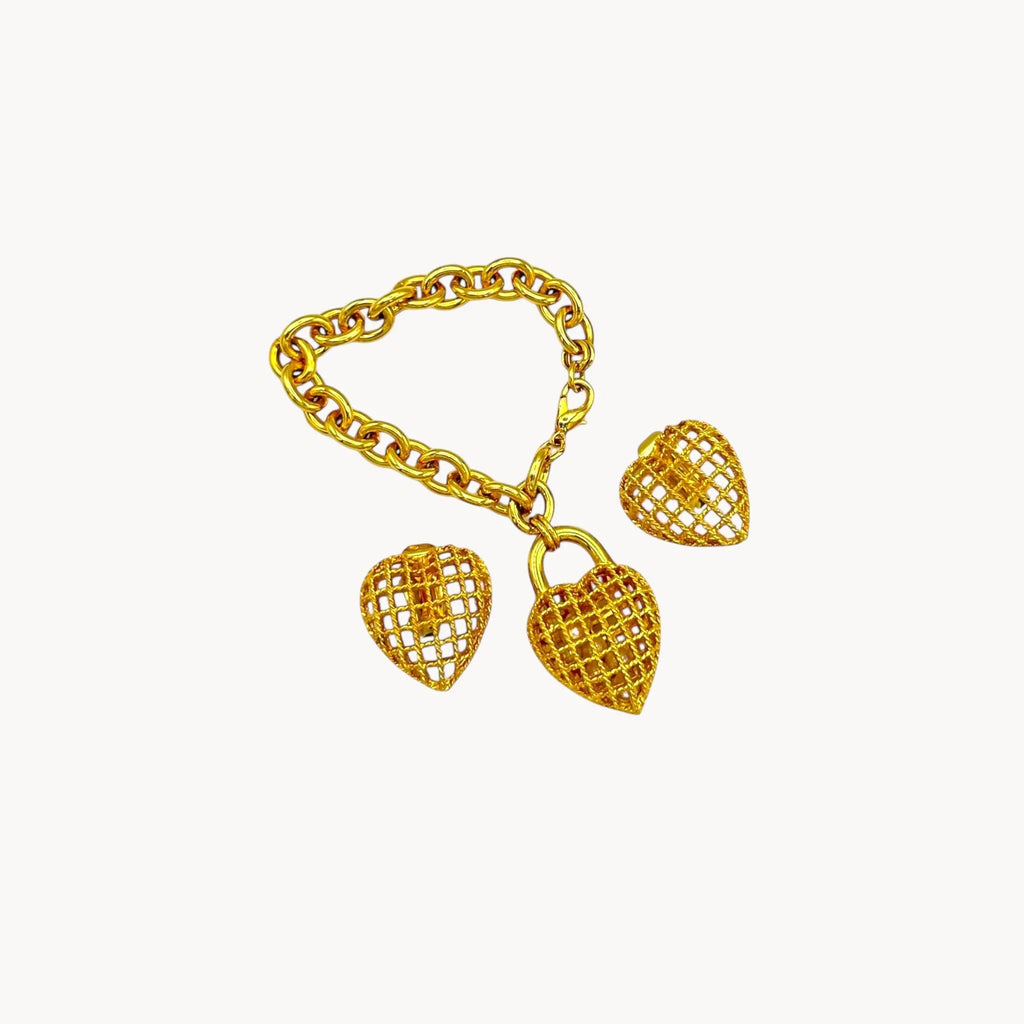 Vintage gold caged pearl heart bracelet and matching clip-on earrings set, 1980s–1990s jewelry on white background flat lay.