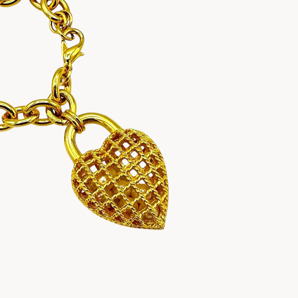 close up view of Bracelet of gold caged pearl heart bracelet and matching clip-on earrings set, 1980s–1990s jewelry on white background.