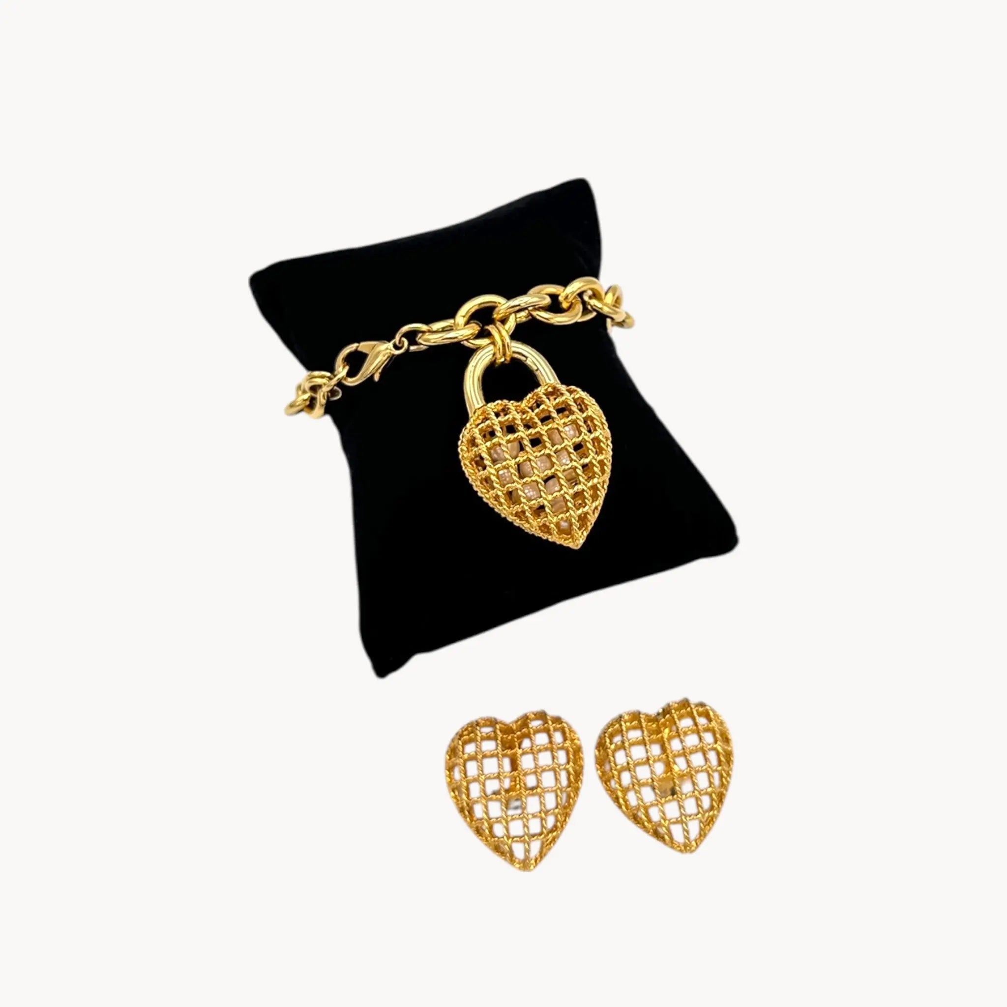 Close up view of Vintage gold caged pearl heart bracelet and matching clip-on earrings set, 1980s–1990s jewelry on white background.