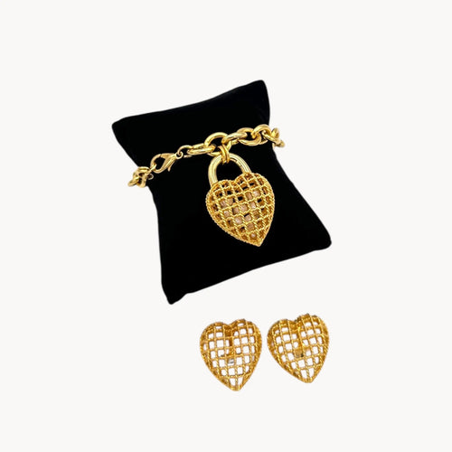 Close up view of Vintage gold caged pearl heart bracelet and matching clip-on earrings set, 1980s–1990s jewelry on white background.
