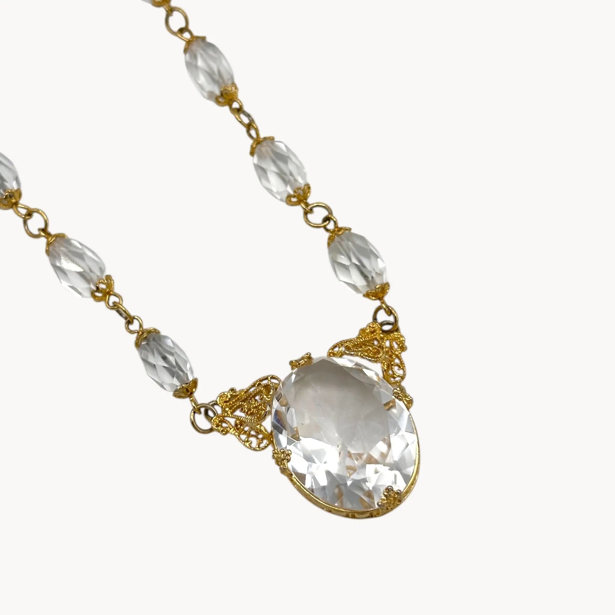 Close up view of Necklace with clear beads and a large crystal pendant on a white background