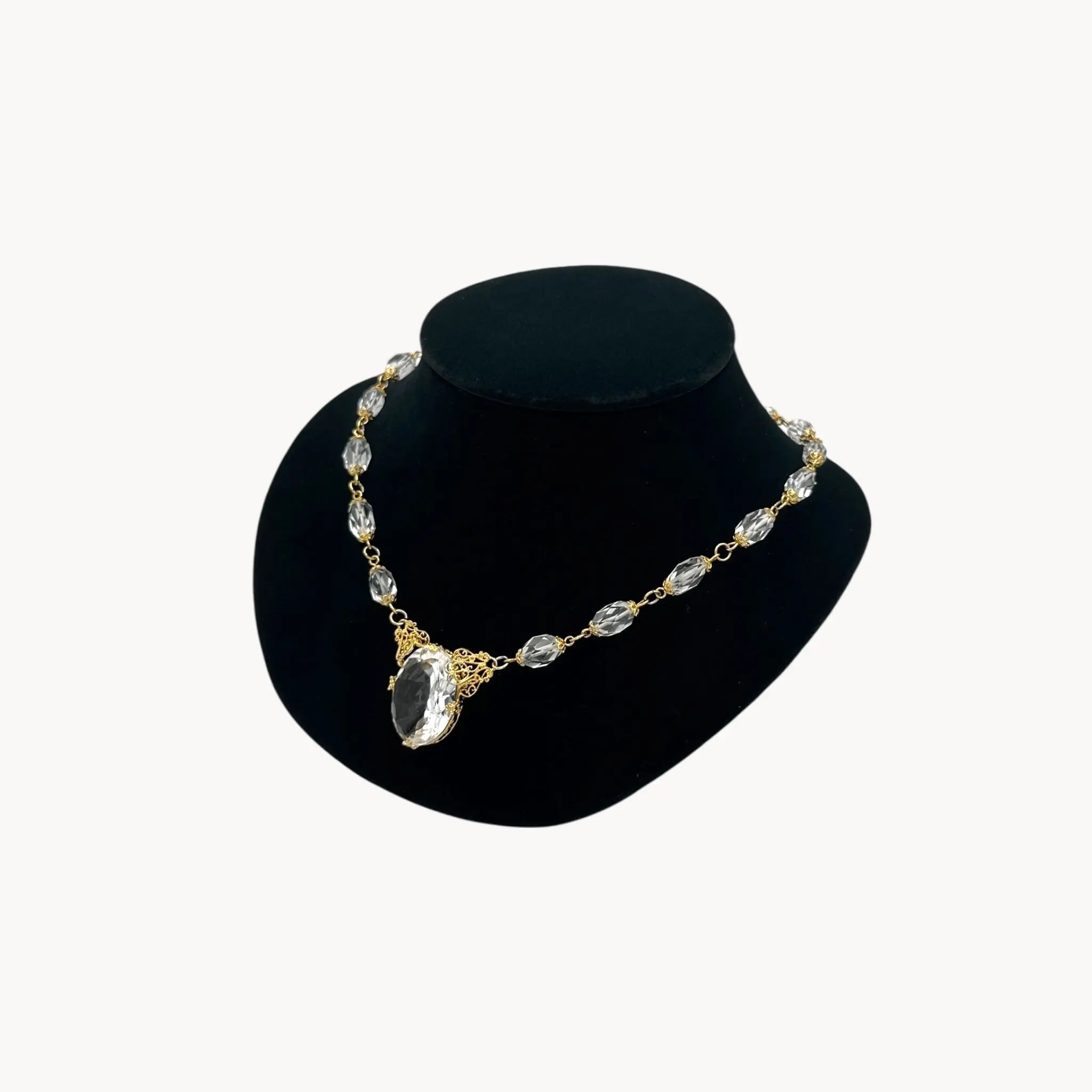 Necklace with gold and clear stones on a black mannequin bust against a white background