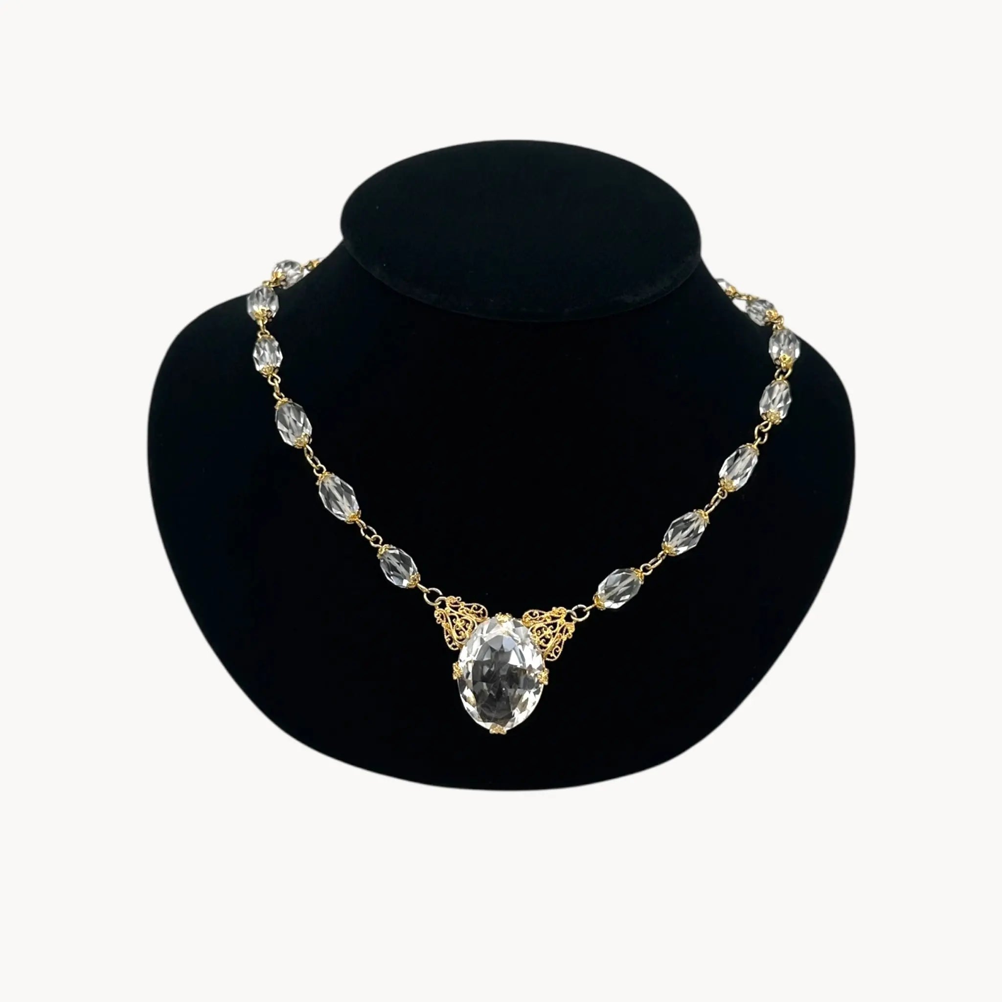 Necklace with clear gemstones on a black mannequin bust against a white background