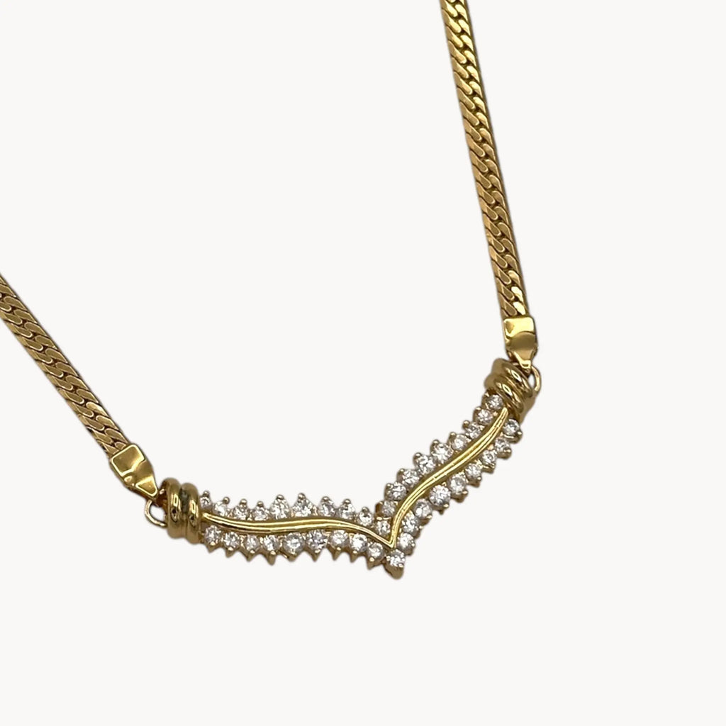 Close up of pendant of Vintage gold rhinestone chevron necklace from the 1980s–1990s on white background.