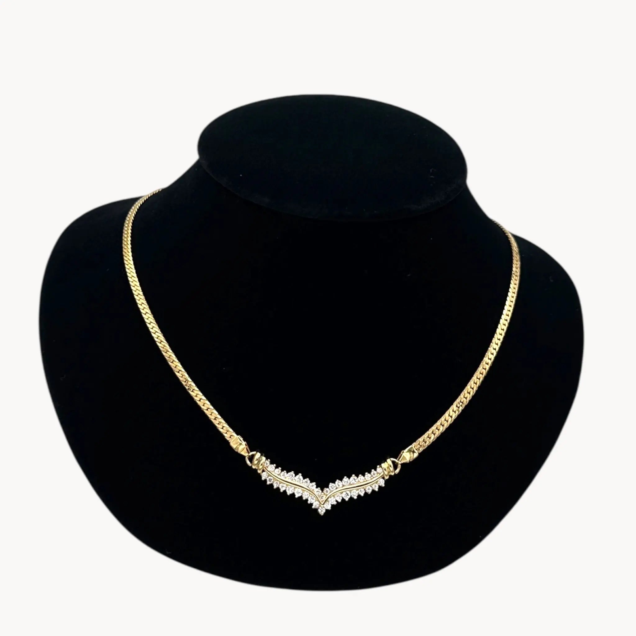 Close up view of Vintage gold rhinestone chevron necklace from the 1980s–1990s on black display bust.