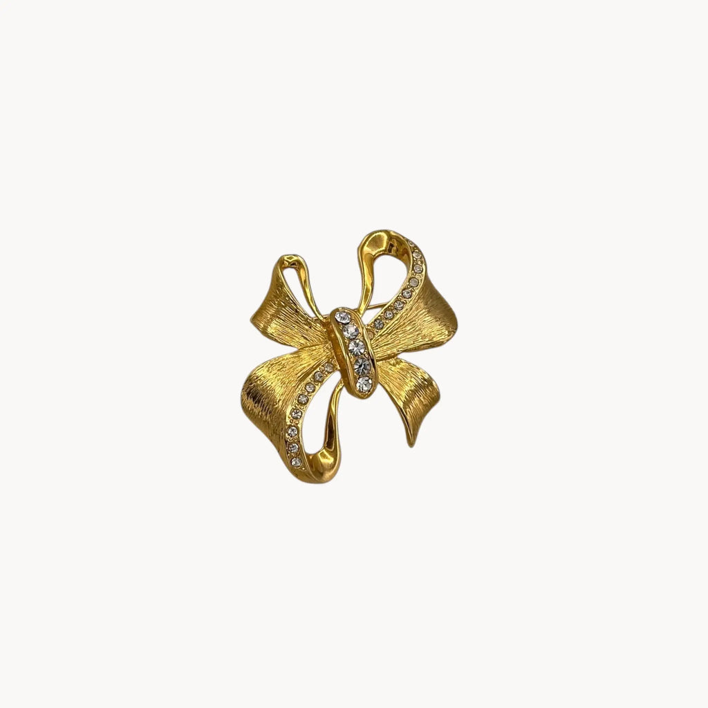 Gold butterfly-shaped brooch with gemstones on a white background