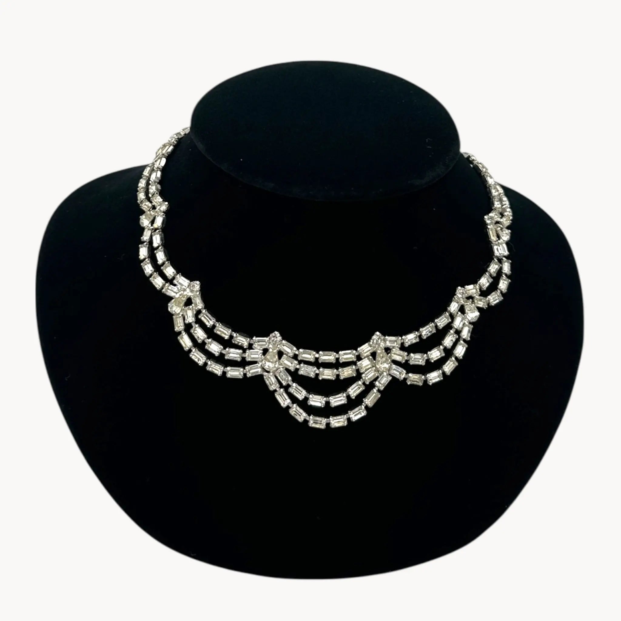 Close up view of Mid-century draped rhinestone necklace with tiered design displayed on black bust.