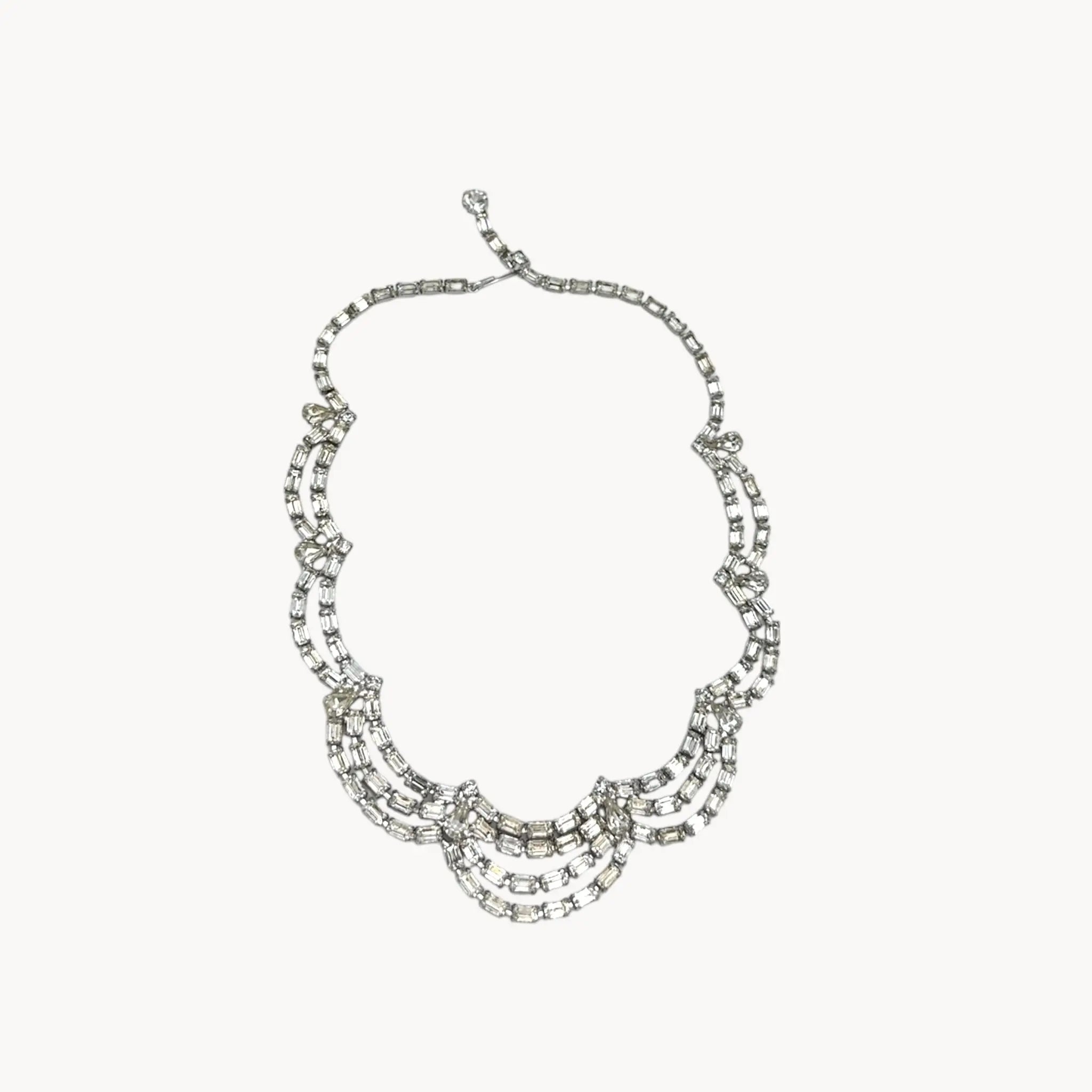 Mid-century draped rhinestone necklace with tiered design displayed on white background.