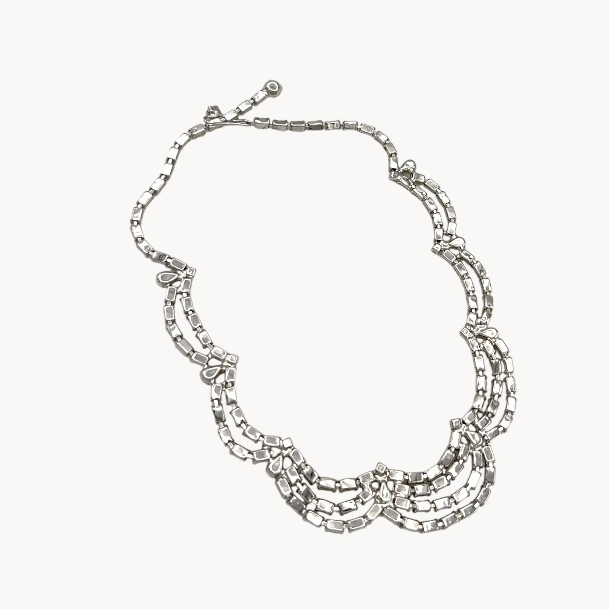 Back view of Mid-century draped rhinestone necklace with tiered design displayed on white background.