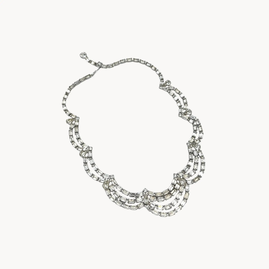 Mid-century draped rhinestone necklace with tiered design displayed on white background.