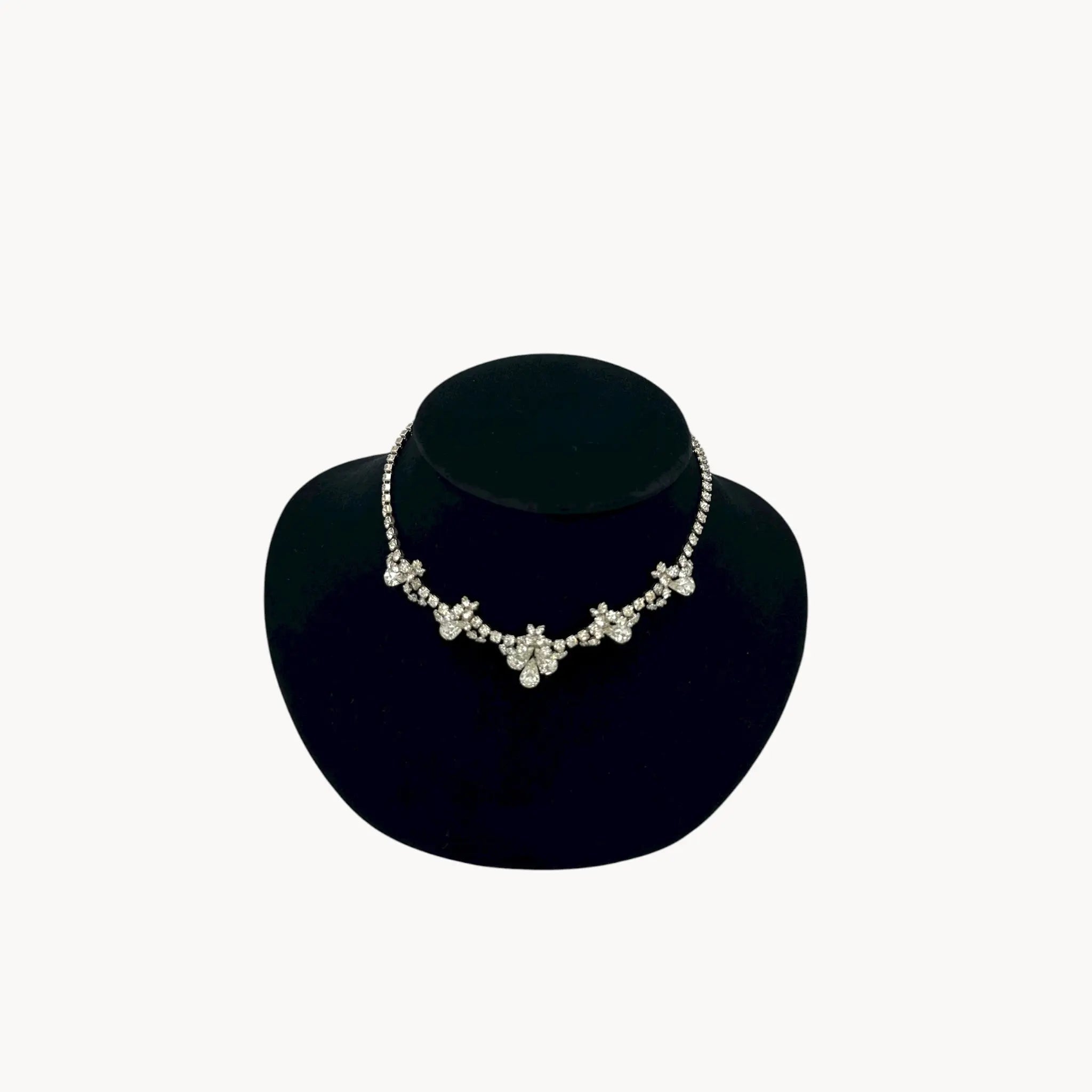 Vintage mid-century teardrop rhinestone necklace with graduated clear crystals on silver setting displayed on black velvet bust.