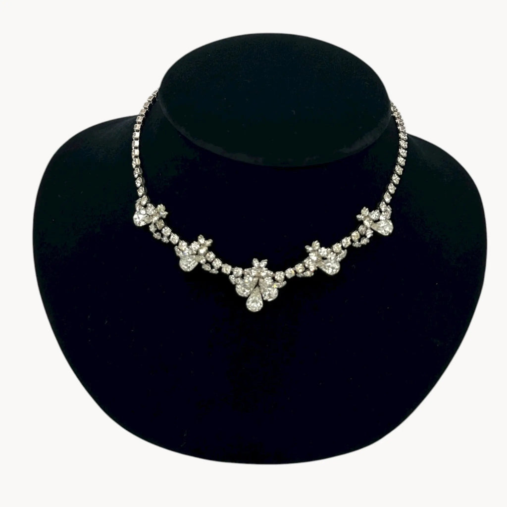 Close up view of Vintage mid-century teardrop rhinestone necklace with graduated clear crystals on silver setting displayed on black velvet bust