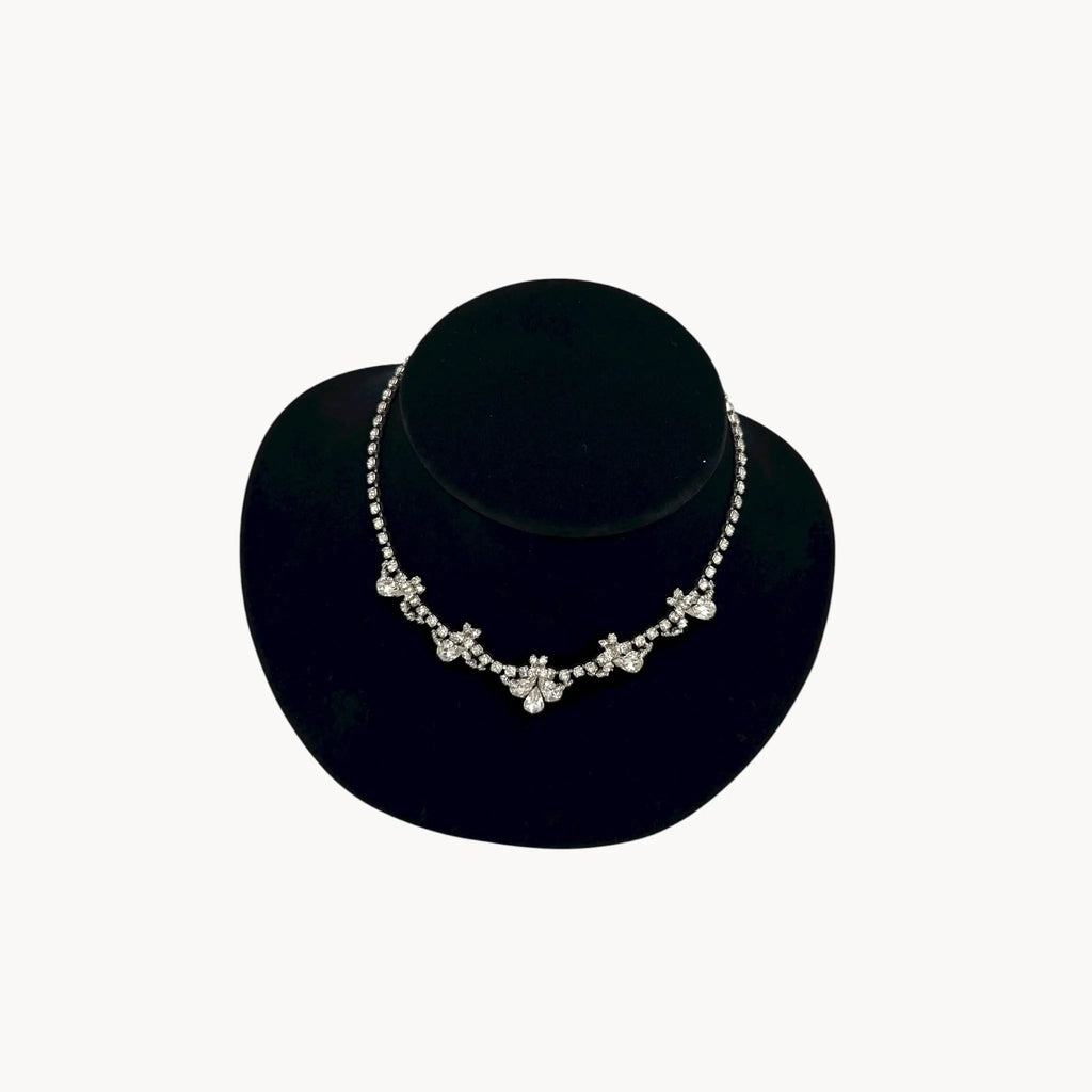 Top view of Vintage mid-century teardrop rhinestone necklace with graduated clear crystals on silver setting displayed on black velvet bust.