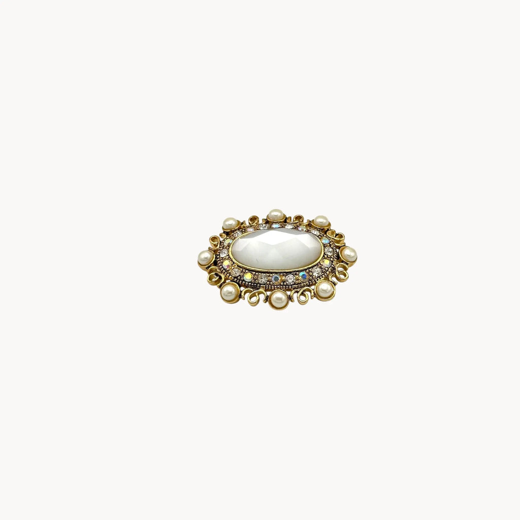 Side view Vintage Monet oval brooch with faceted glass center, faux pearls, and crystal accents.