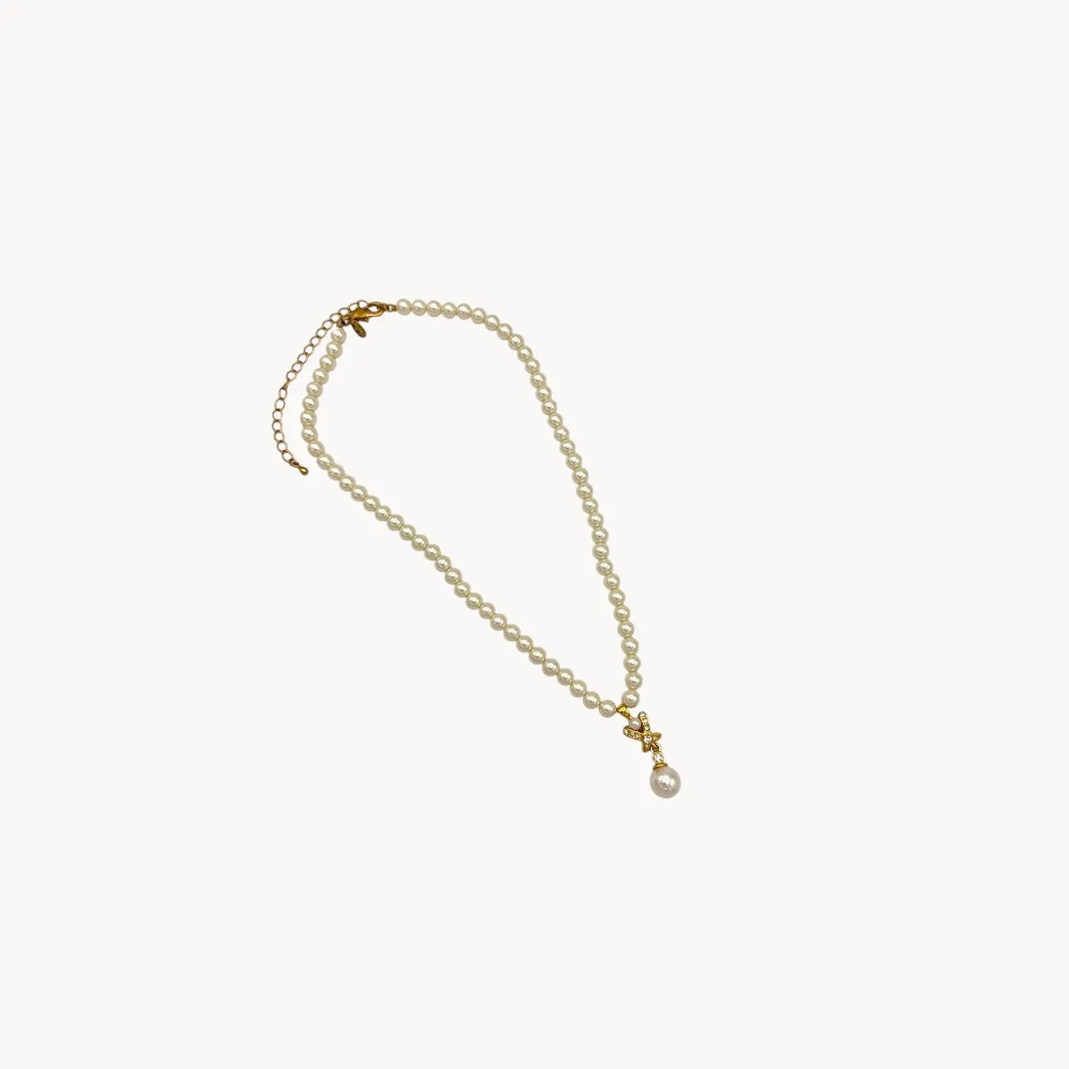 Against white background Vintage Napier faux pearl necklace with rhinestone X motif and pearl drop pendant.