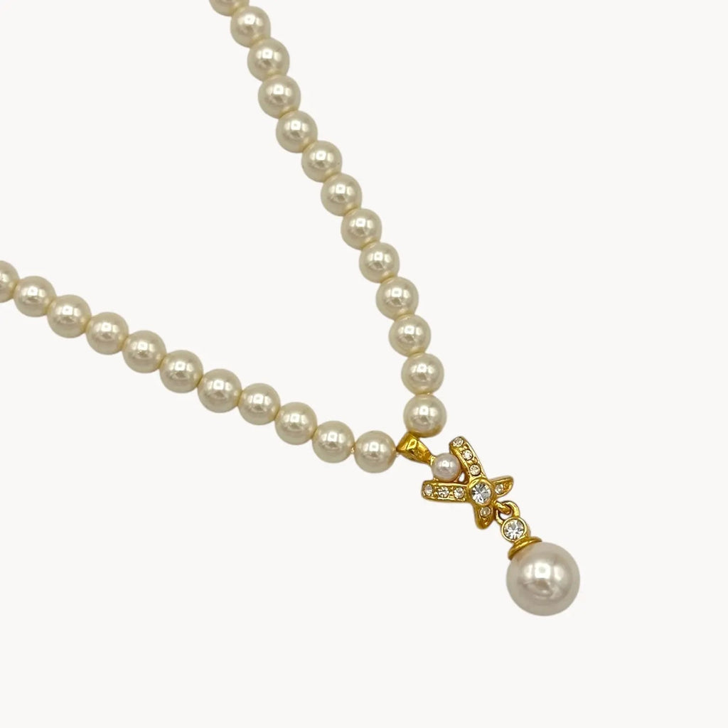 Close up of pendant of Vintage Napier faux pearl necklace with rhinestone X motif and pearl drop pendant.
