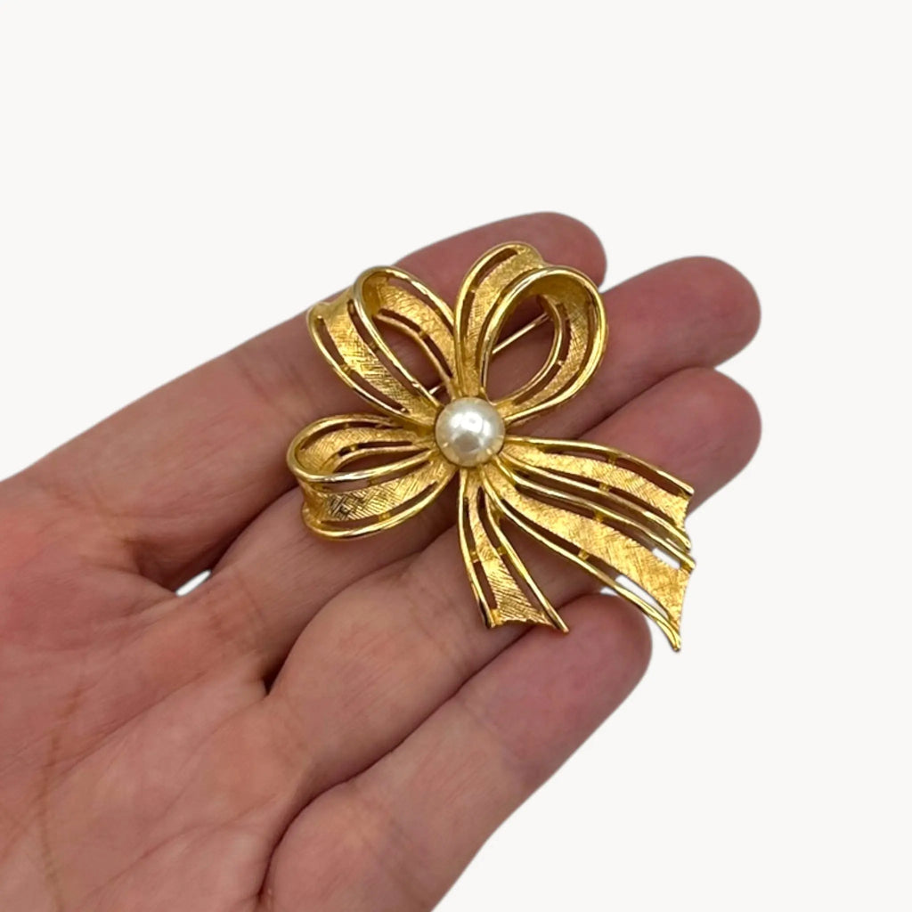 Close up view of Vintage Napier gold ribbon bow brooch with pearl center.