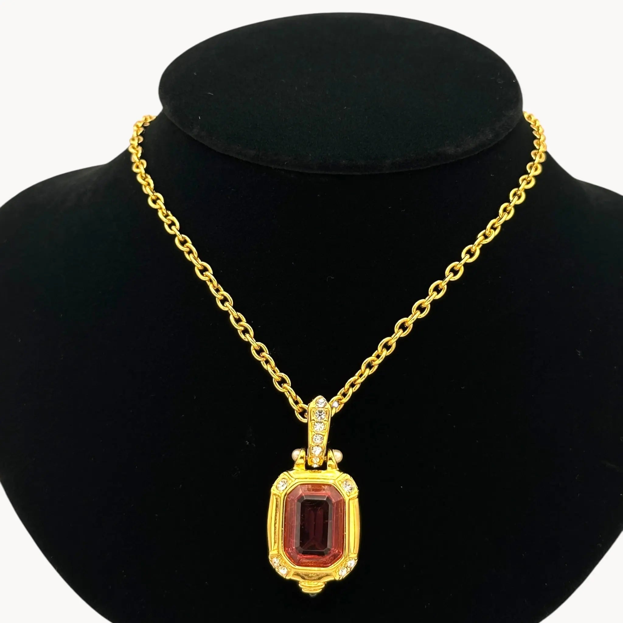 Close up view of Vintage Nolan Miller long gold chain necklace with pink crystal pendant and clear crystal accents, 1980s–1990s bridal jewelry shown on black bust.