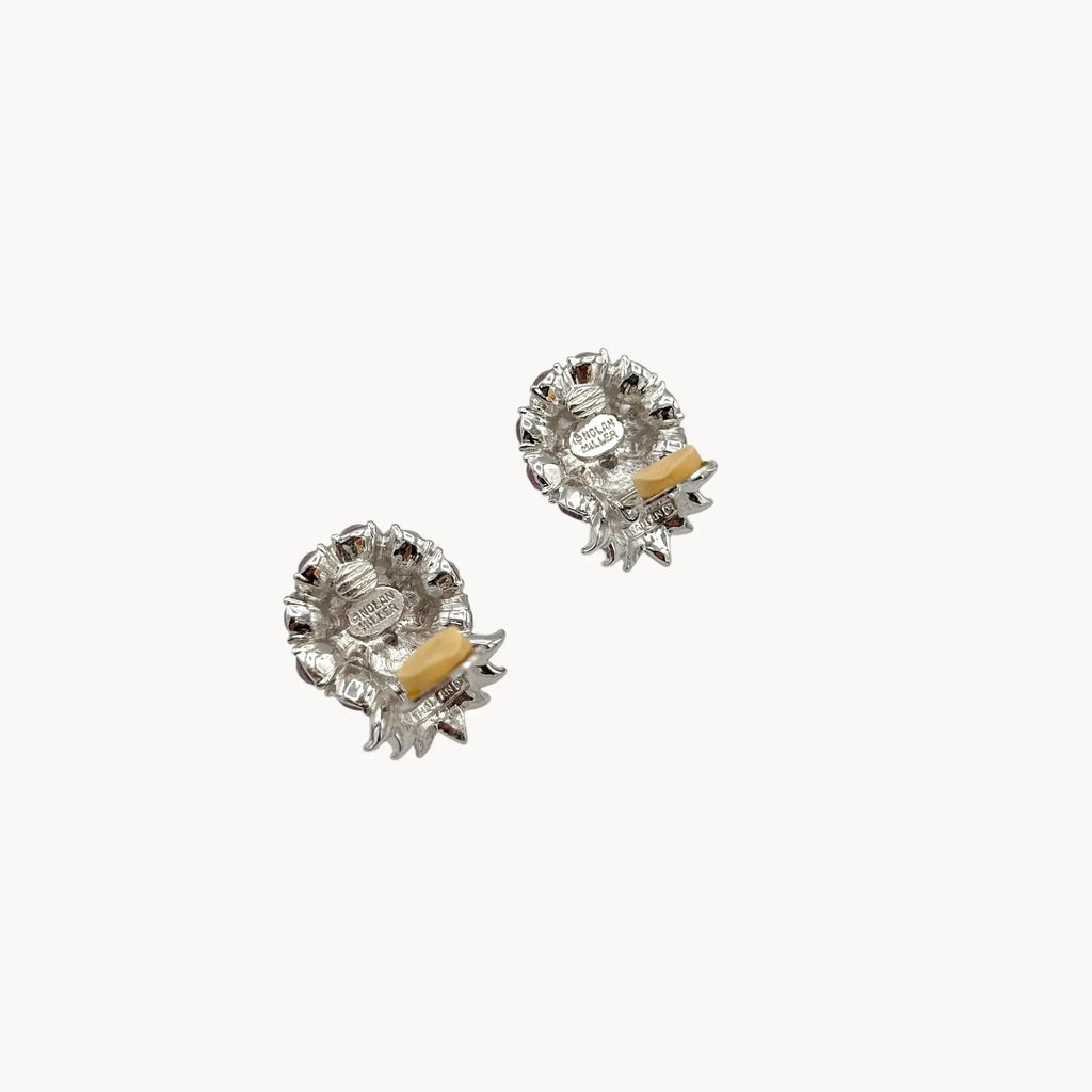 Back view with clips open of Vintage Nolan Miller rhinestone floral clip-on earrings with silver-tone leaves