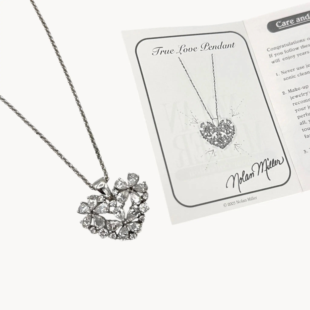 Close up view of Vintage Nolan Miller rhinestone heart pendant necklace on silver chain.