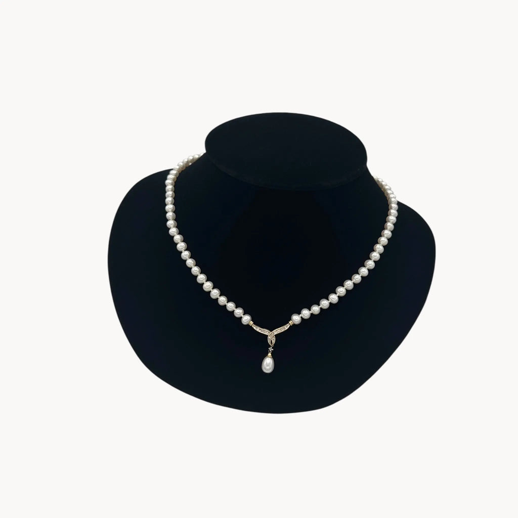 Vintage Pearl Strand Necklace with 10K Gold & Diamond Drop Pendant on black bust and white background.