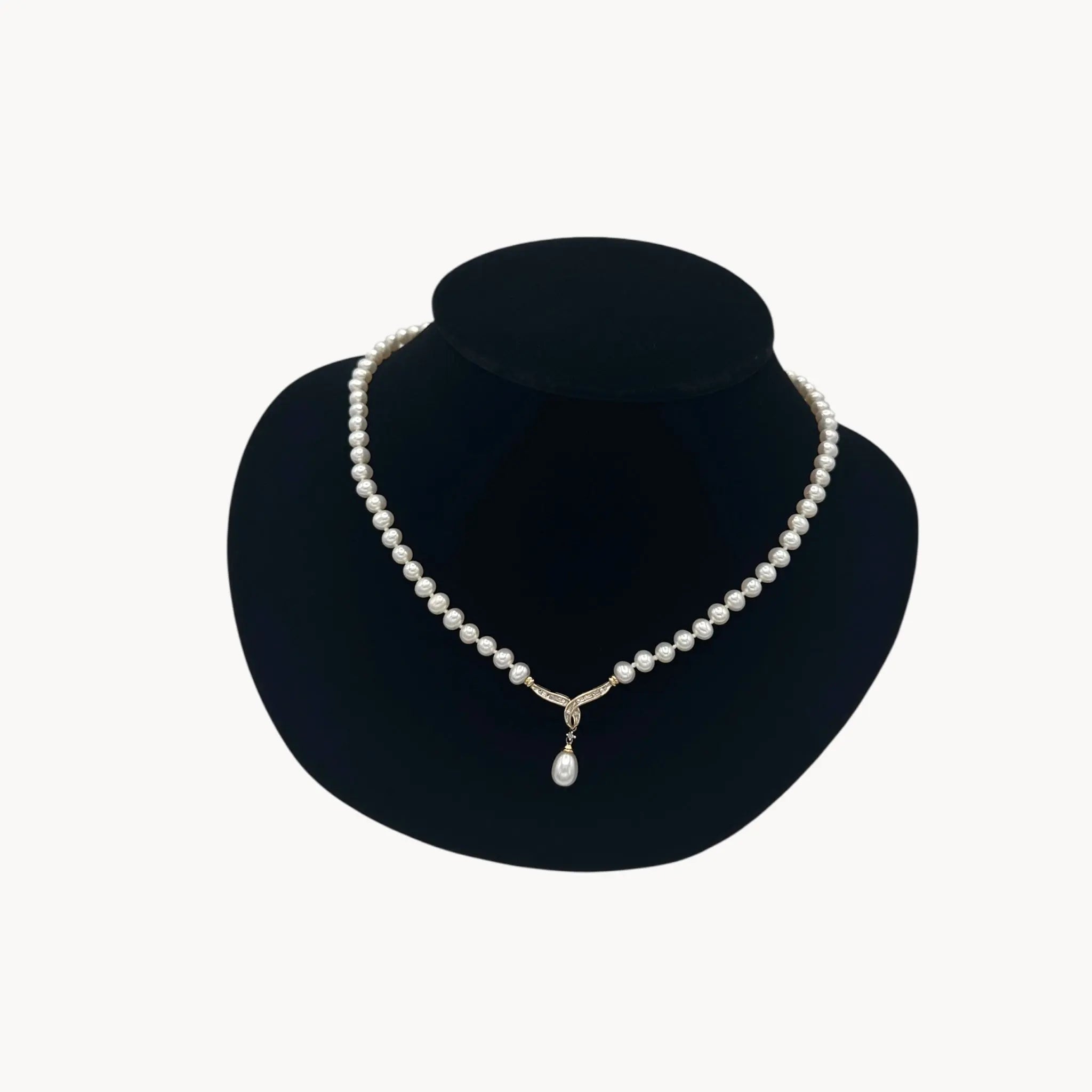 Vintage Pearl Strand Necklace with 10K Gold & Diamond Drop Pendant on black bust and white background.