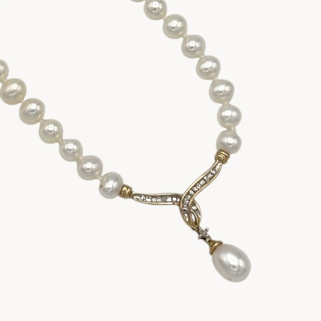 Close up of pendant Vintage pearl strand necklace with 10K gold and diamond drop pendant, bridal jewelry on white background.