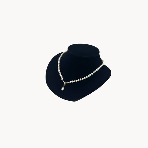 Side view of Vintage pearl strand necklace with 10K gold and diamond drop pendant, bridal jewelry on white background.