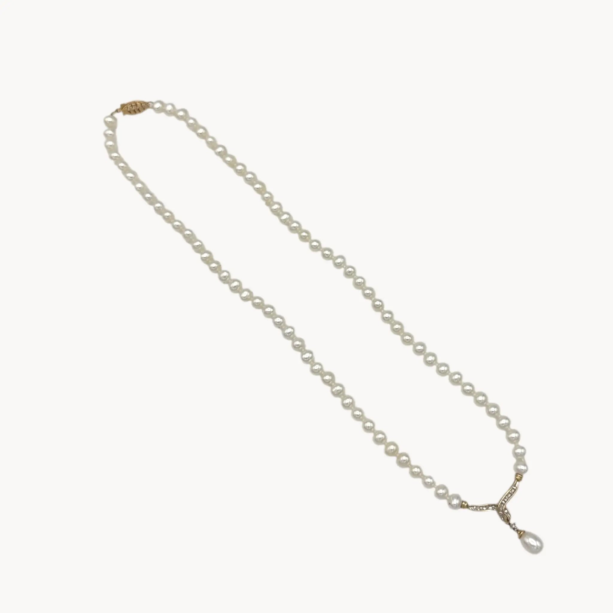 Vintage pearl strand necklace with 10K gold and diamond drop pendant, bridal jewelry on white background.