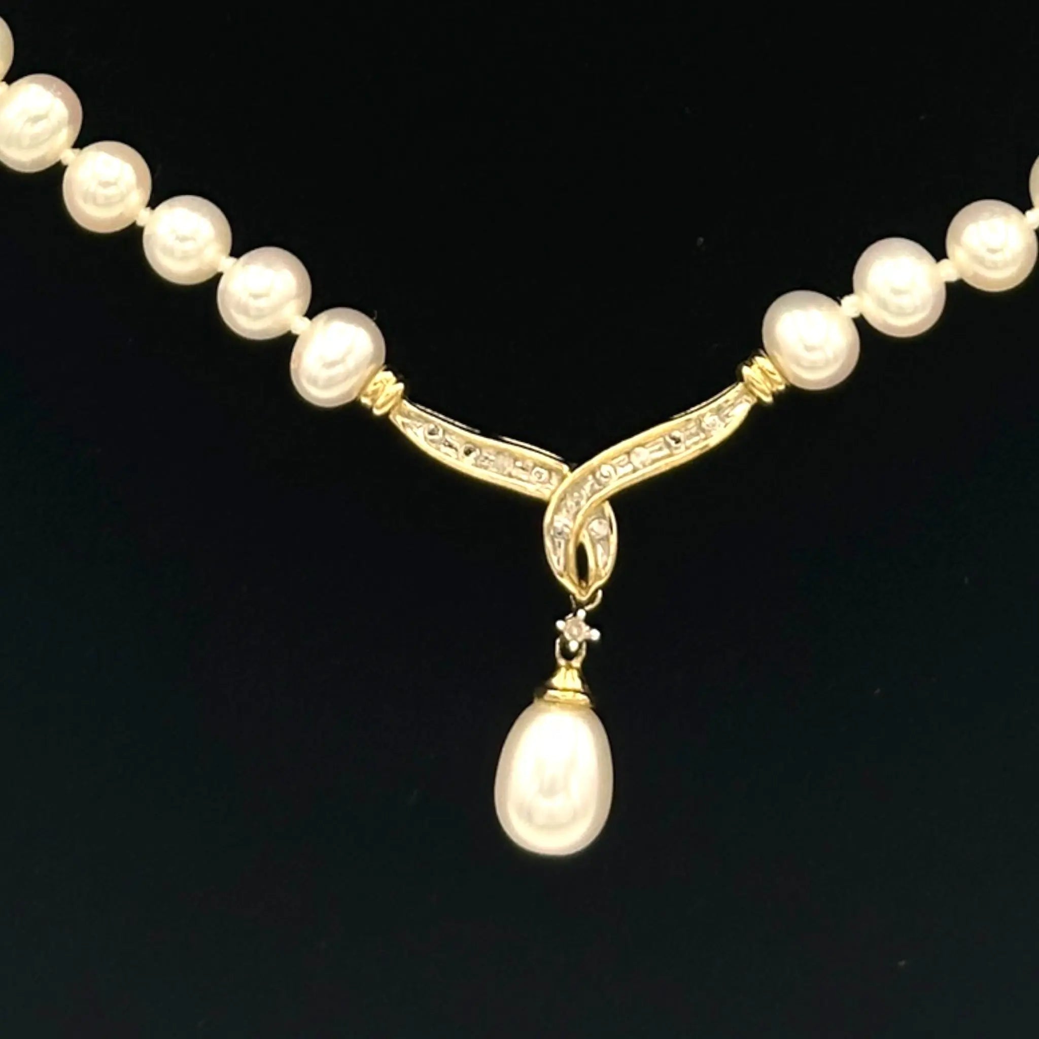 Vintage pearl strand necklace with 10K gold and diamond drop pendant, bridal jewelry on black background.
