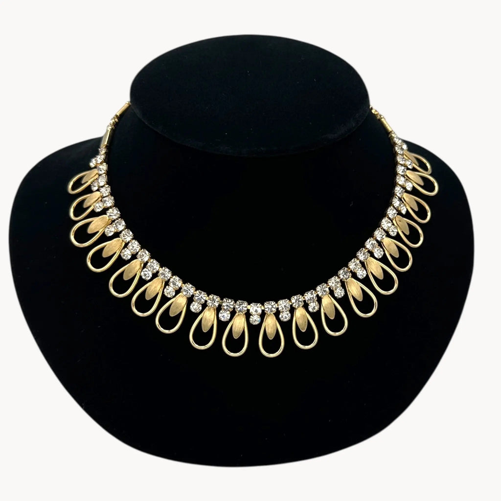 Close up view of Vintage Sarah Coventry gold-tone teardrop bib necklace with clear rhinestones displayed on black velvet bust