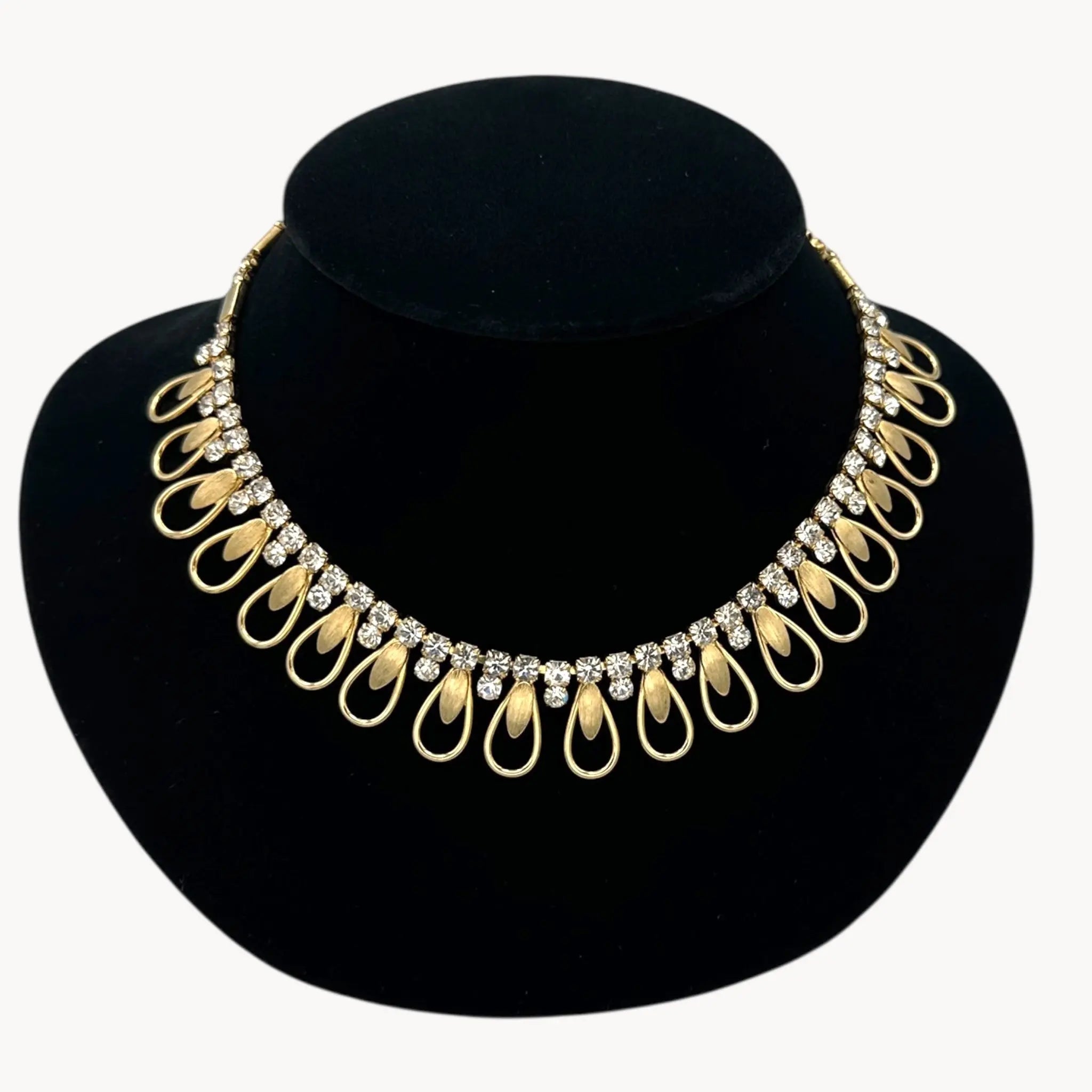 Close up view of Vintage Sarah Coventry gold-tone teardrop bib necklace with clear rhinestones displayed on black velvet bust