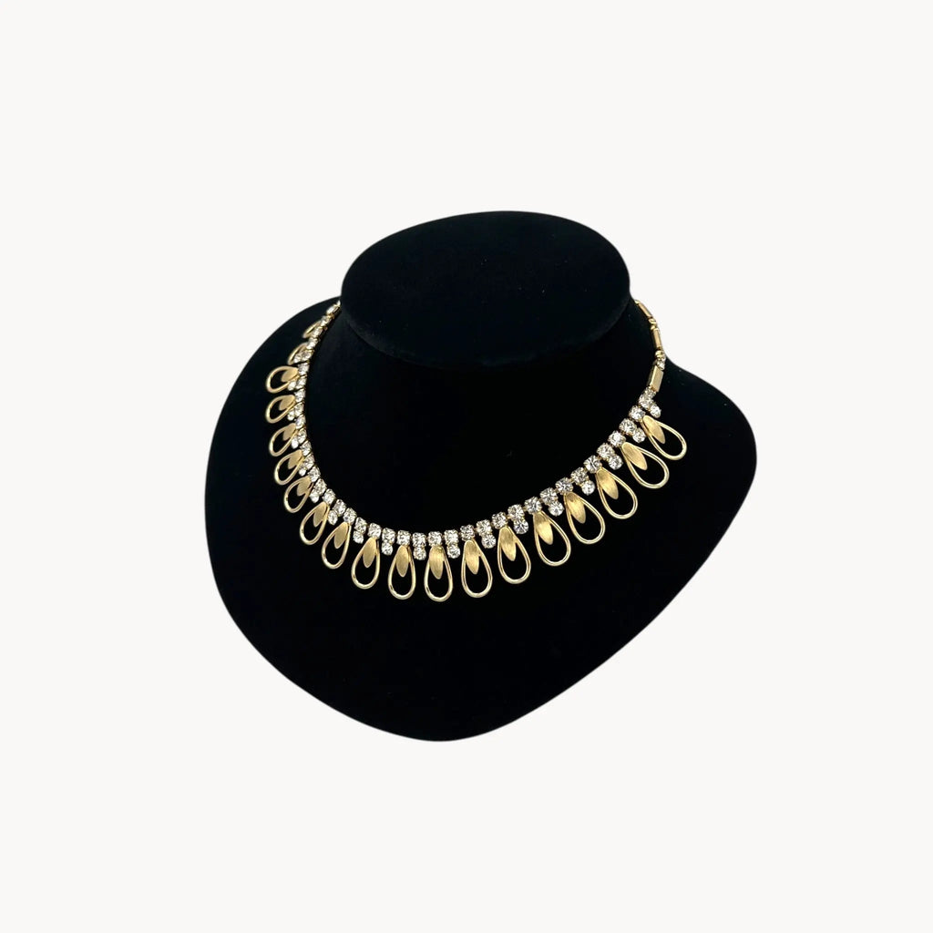 Side view of Vintage Sarah Coventry gold-tone teardrop bib necklace with clear rhinestones displayed on black velvet bust