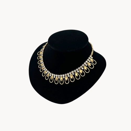 Side view of Vintage Sarah Coventry gold-tone teardrop bib necklace with clear rhinestones displayed on black velvet bust