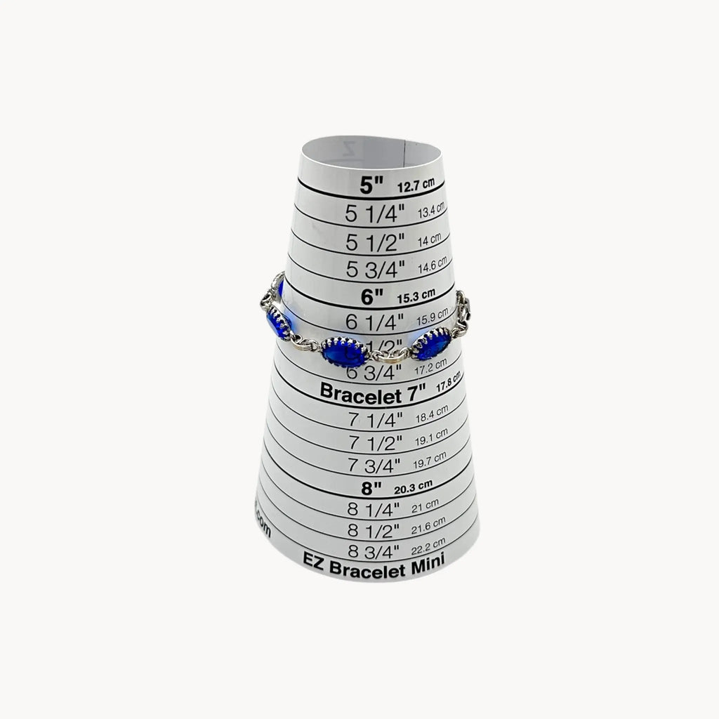 On sizer view of Vintage sterling silver blue glass link bracelet with oval sapphire-toned stones, mid-century bridal jewelry.