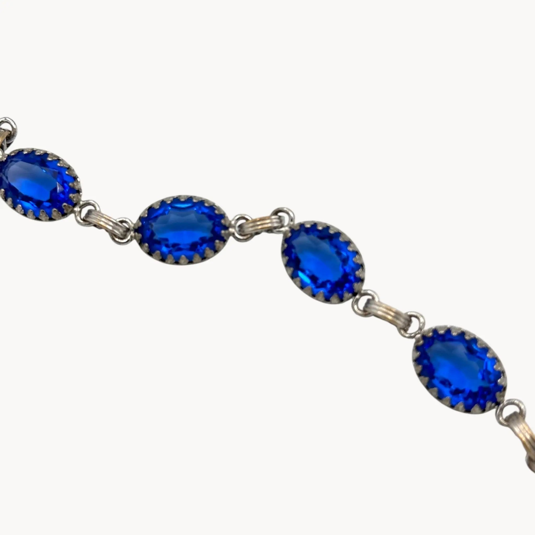 Close up view of Vintage sterling silver blue glass link bracelet with oval sapphire-toned stones, mid-century bridal jewelry.