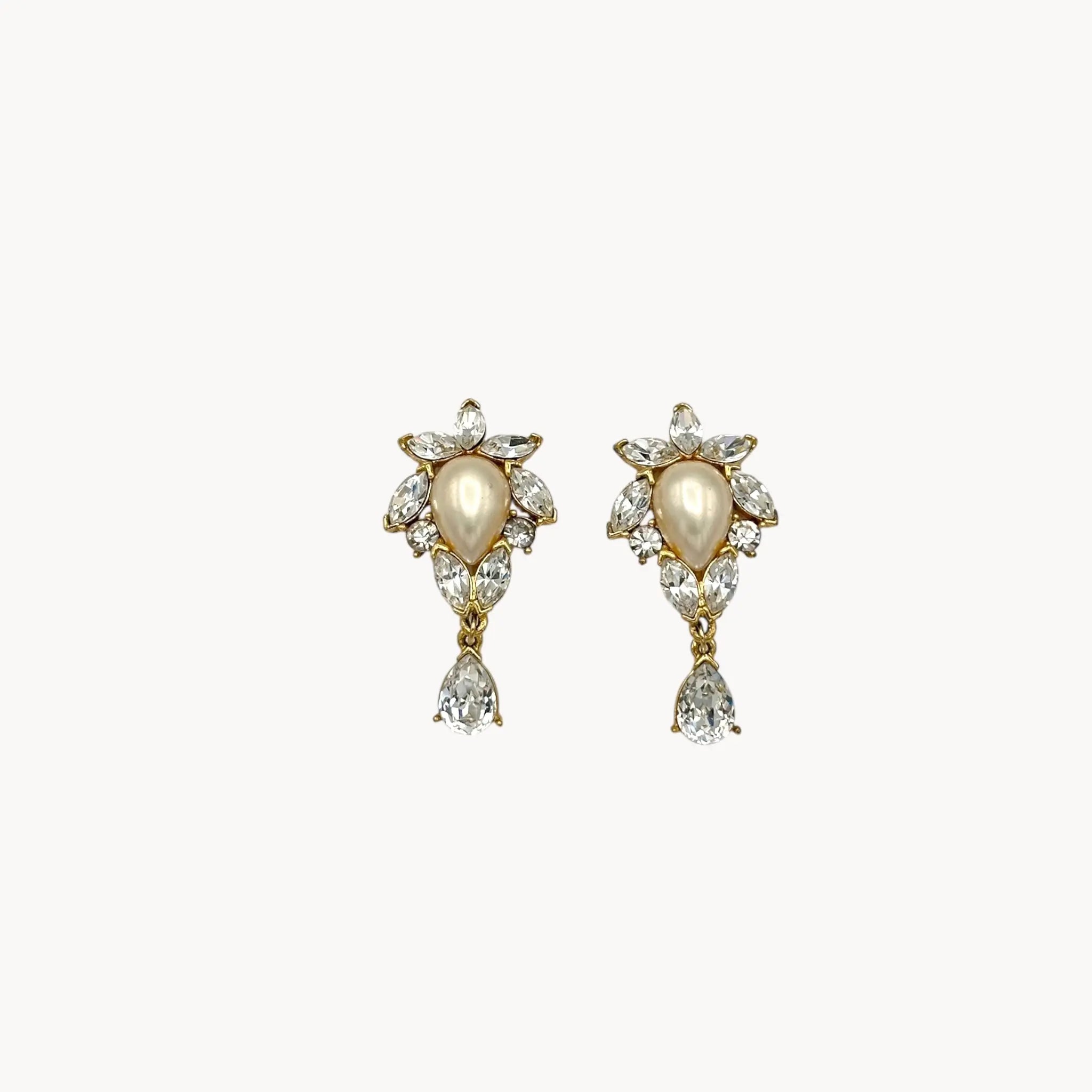 Close up view of 1990s Trifari faux pearl and crystal clip-on earrings in gold-tone with teardrop design, vintage bridal jewelry.