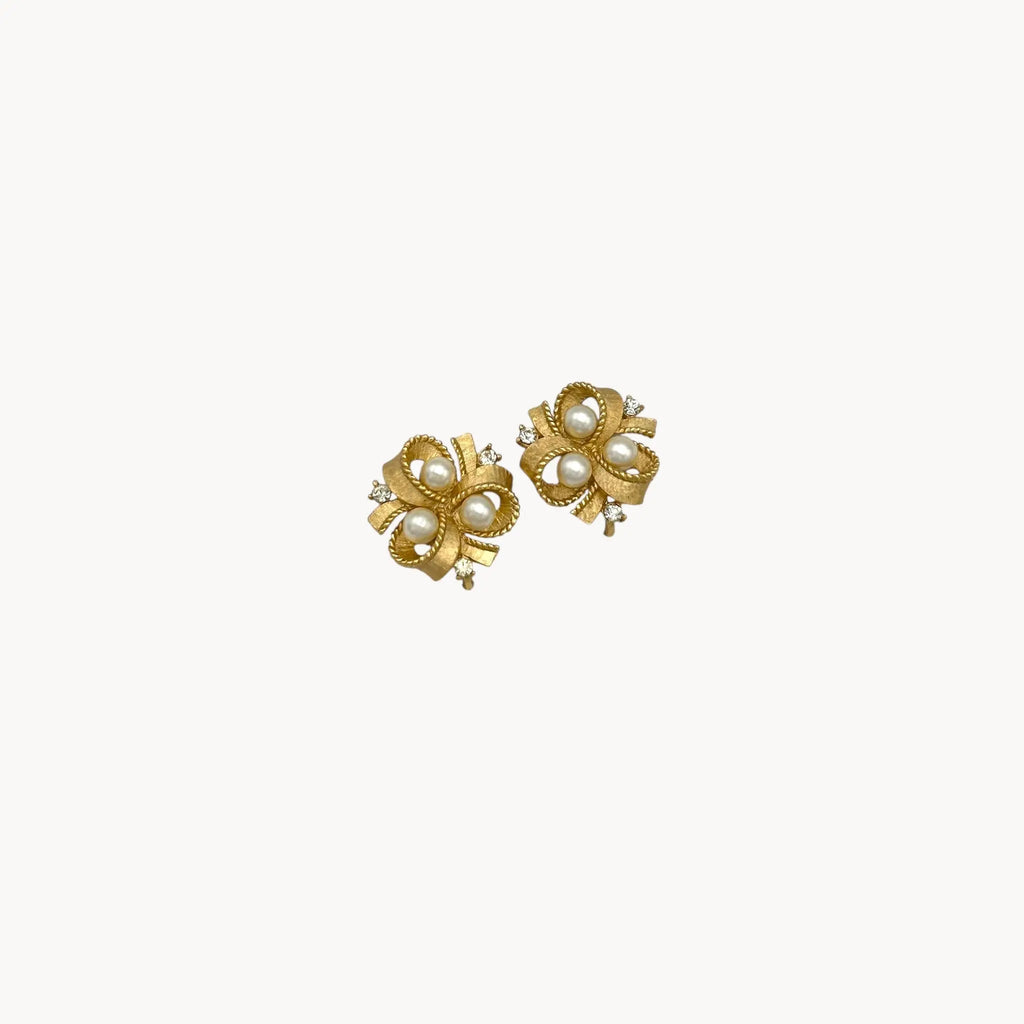 zoom in Vintage Trifari clip-on earrings with gold bow design, faux pearls, and crystal accents, 1960s bridal jewelry.