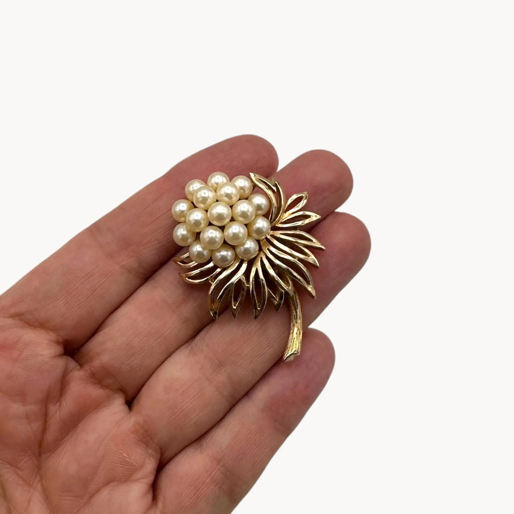 Scale size view of Vintage Trifari gold tone flower brooch with faux pearl cluster.