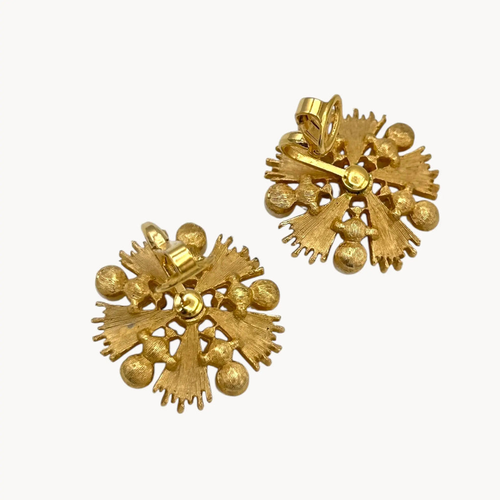 Back view with backs up of Trifari gold starburst clip-on earrings with faux pearls and rhinestones, 1960s jewelry on white background.