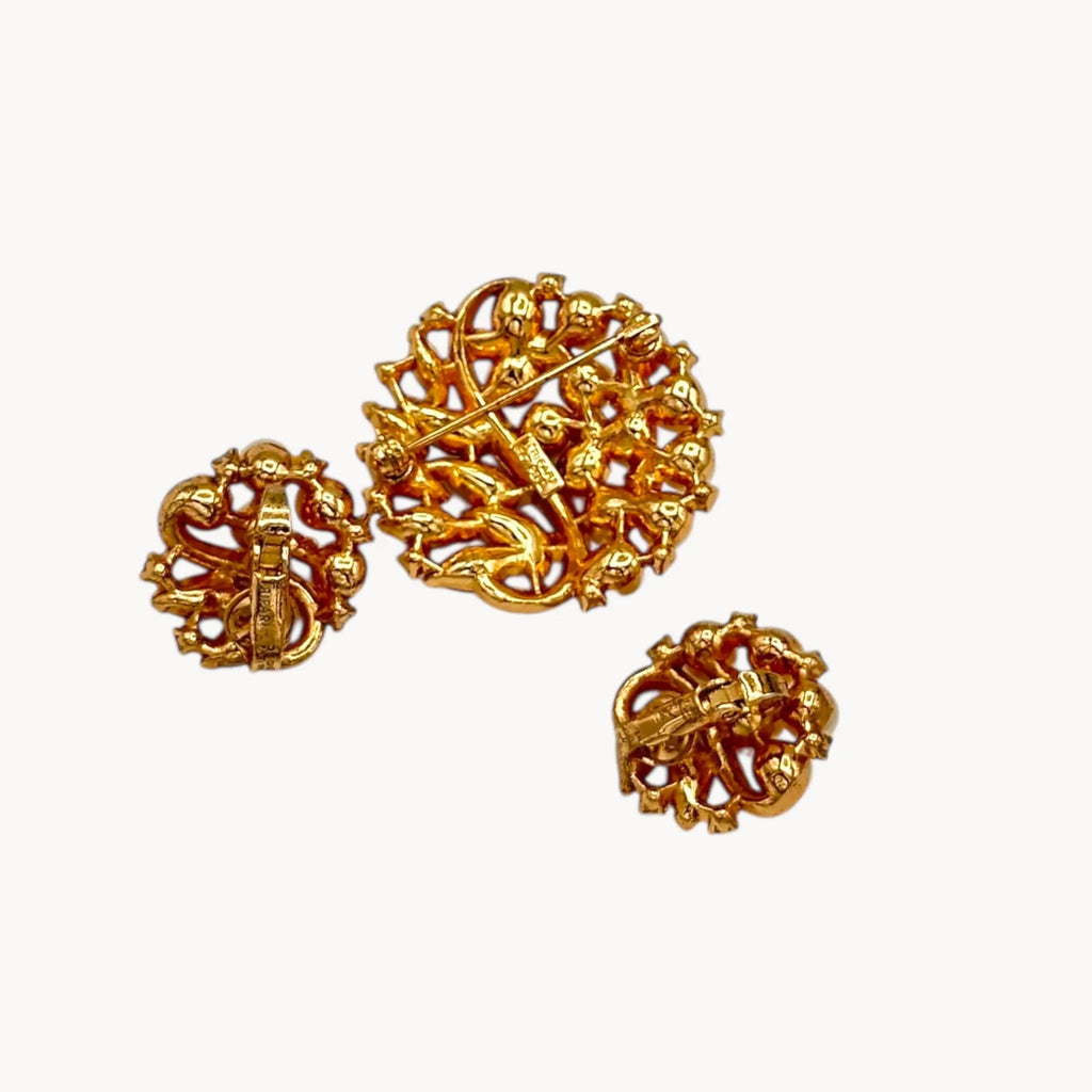 Back view of Brooch of the Vintage Trifari brooch with faux pearls, rhinestones, and gold-tone design shown on white background.