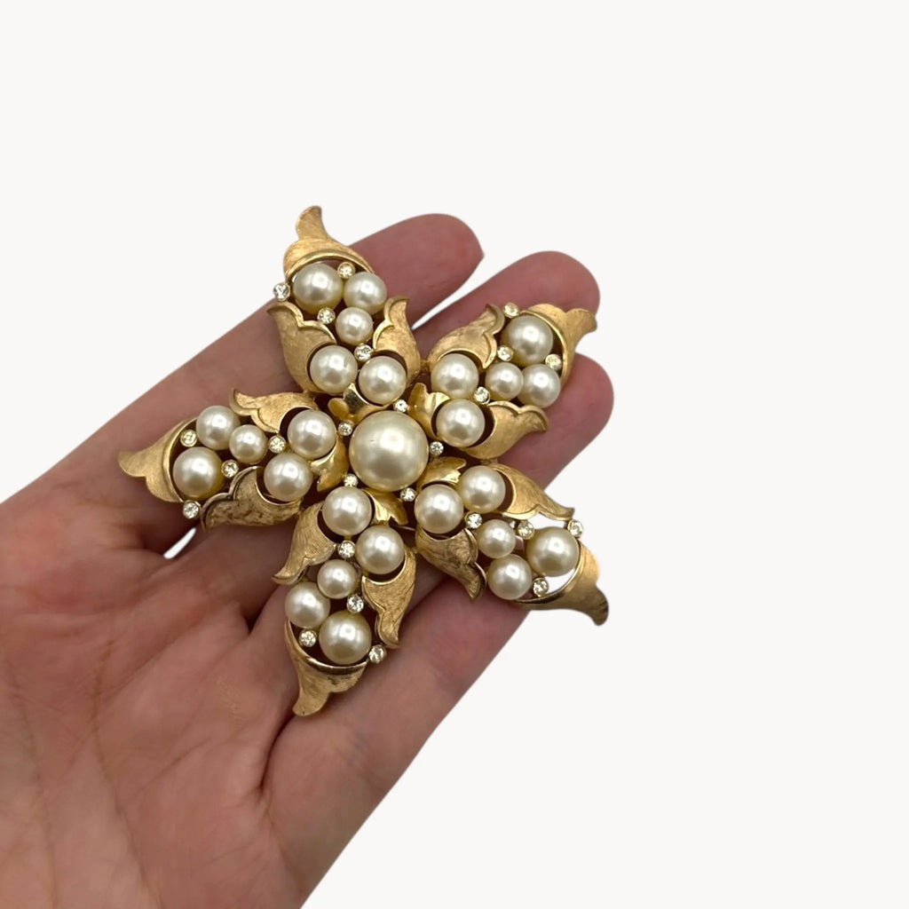 Scale view of Vintage Trifari floral starfish brooch with faux pearls and rhinestones in gold-tone metal.