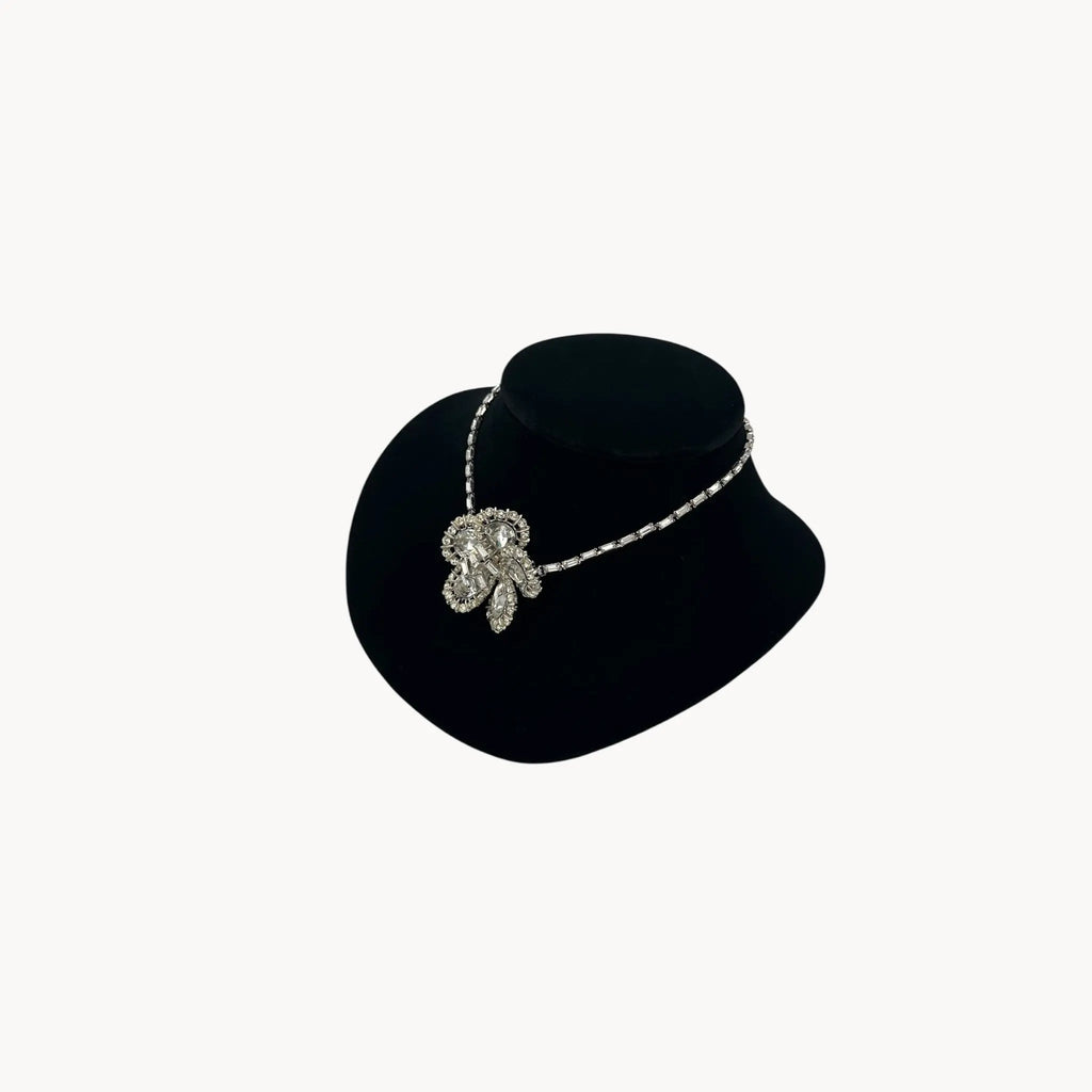 Side view of Large Trifari Rhinestone Floral Necklace on black bust.