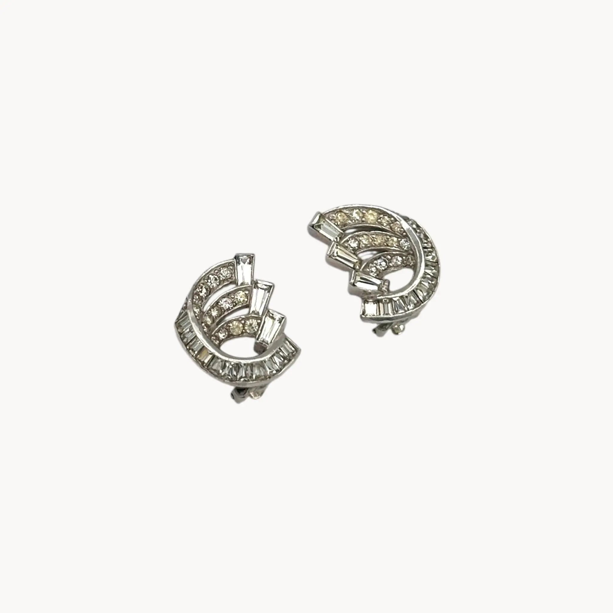 Side view of Weiss vintage clip-on rhinestone earrings with baguette and round stones in silver-tone setting.
